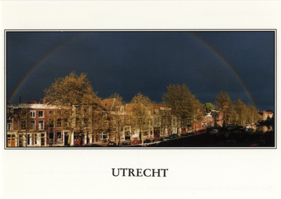 601978 Afbeelding van een regenboog in een donkere lucht met op de voorgrond de door de zon beschenen voorgevels van de ...